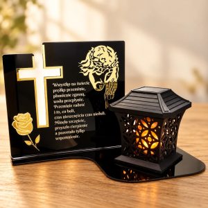 Czarna tabliczka pamięci z akrylu ze złotym krzyżem, różą, wizerunkiem Jezusa i wierszem, obok czarny ażurowy lampion LED